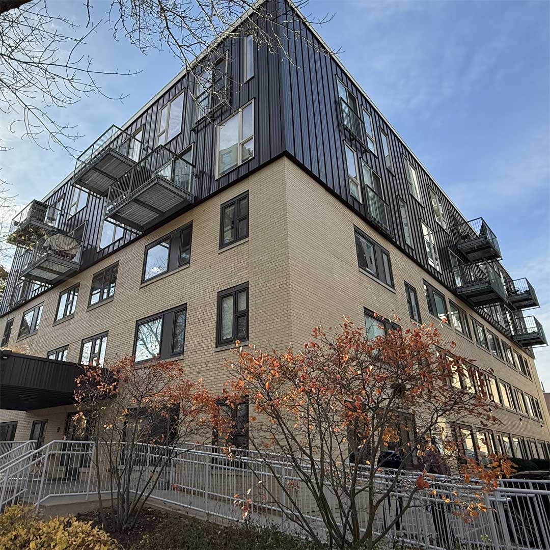 Exterior view of a modern multi‑story residential building with balconies, brick facade, and contemporary architectural design.