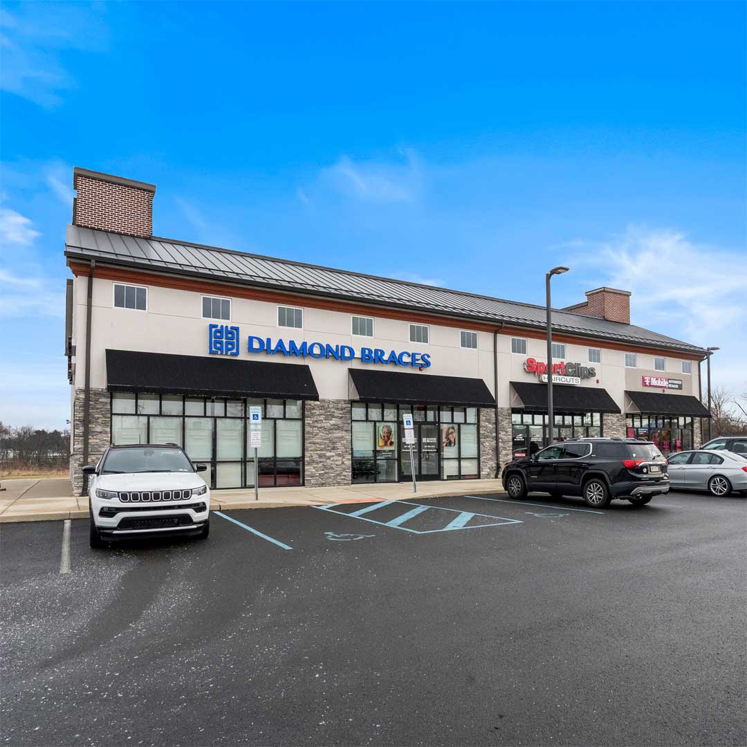 Exterior view of a retail strip center featuring Diamond Braces and other storefronts with parking spaces in front.