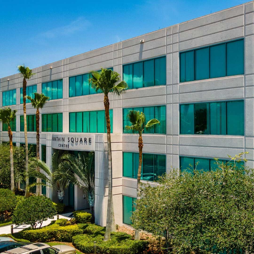 Modern Fountain Square Centre office building with teal glass windows, palm trees, and landscaped entrance under clear blue sky.