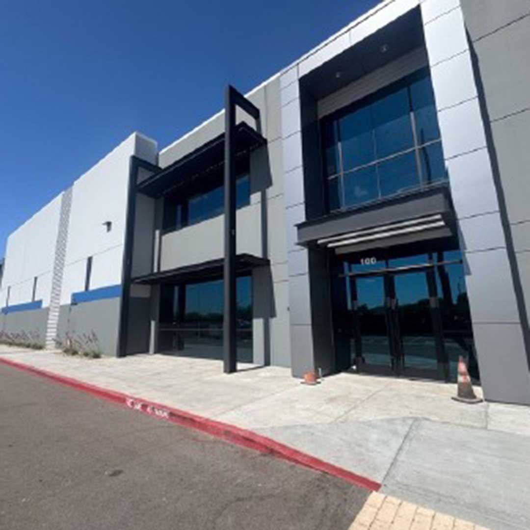 Modern industrial warehouse with two-story office frontage, large glass windows, and main entrance under clear bl