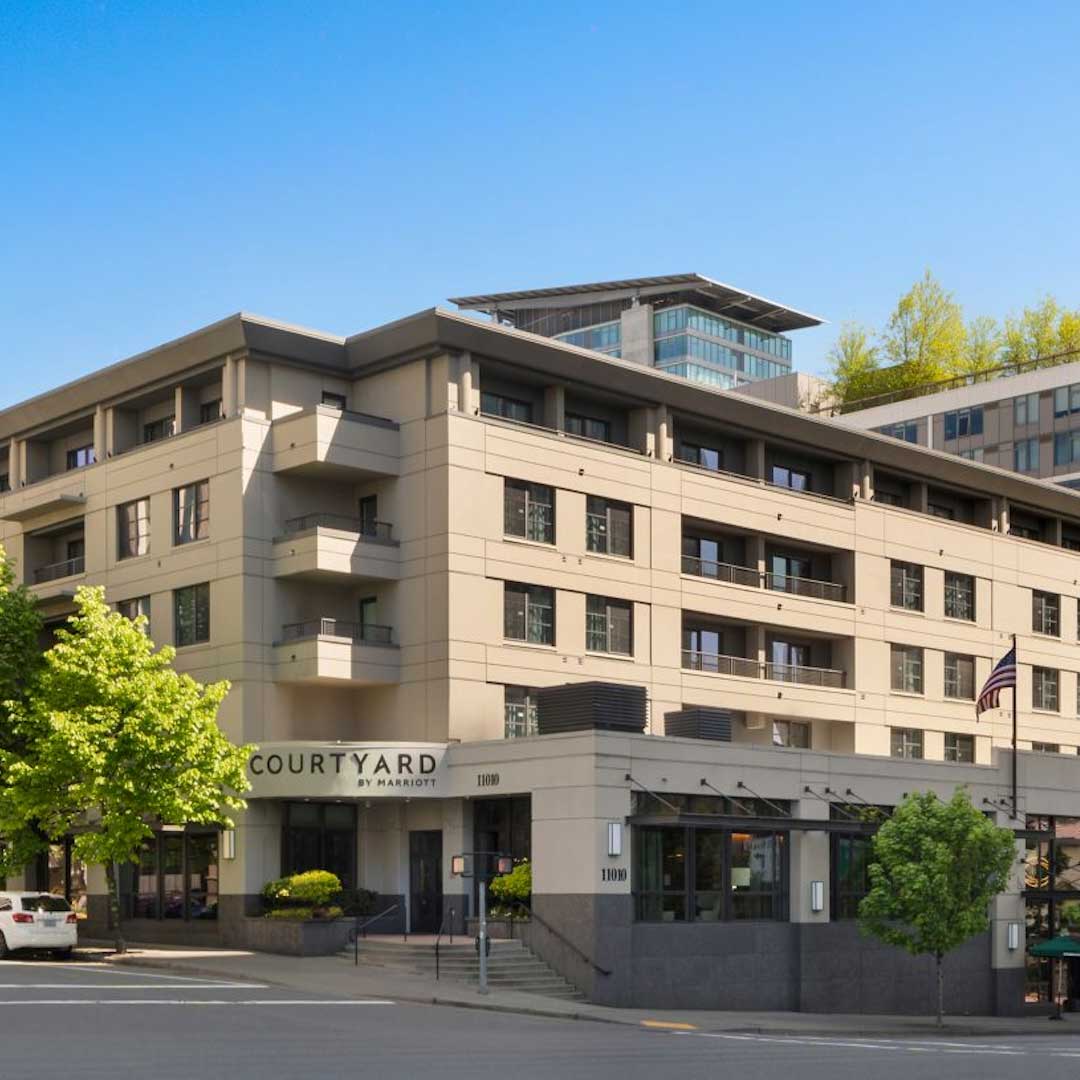 Exterior view of Courtyard by Marriott hotel building with modern architecture, balconies, and main entrance in an urban setting.