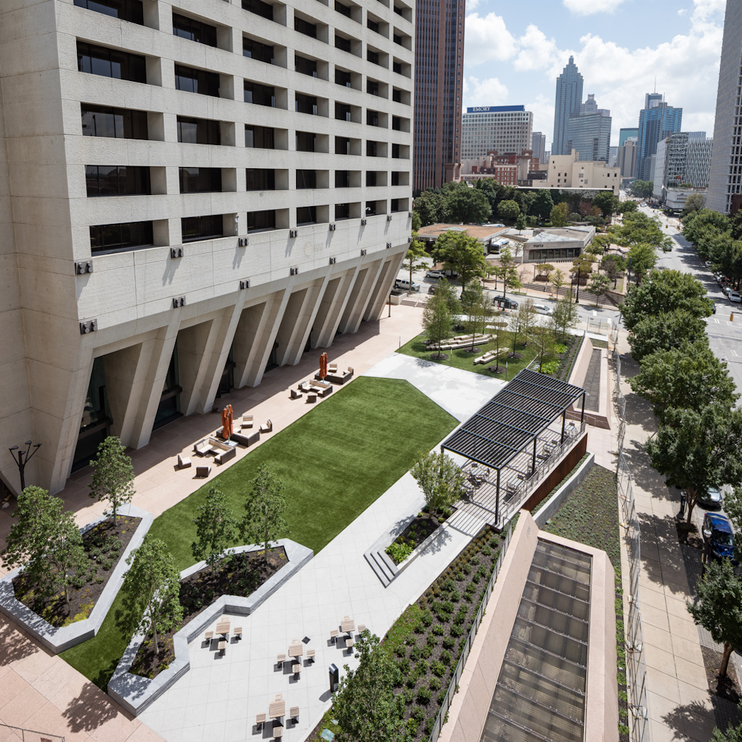 Aerial view of urban office building with landscaped courtyard, seating areas, and pergola in a downtown business district