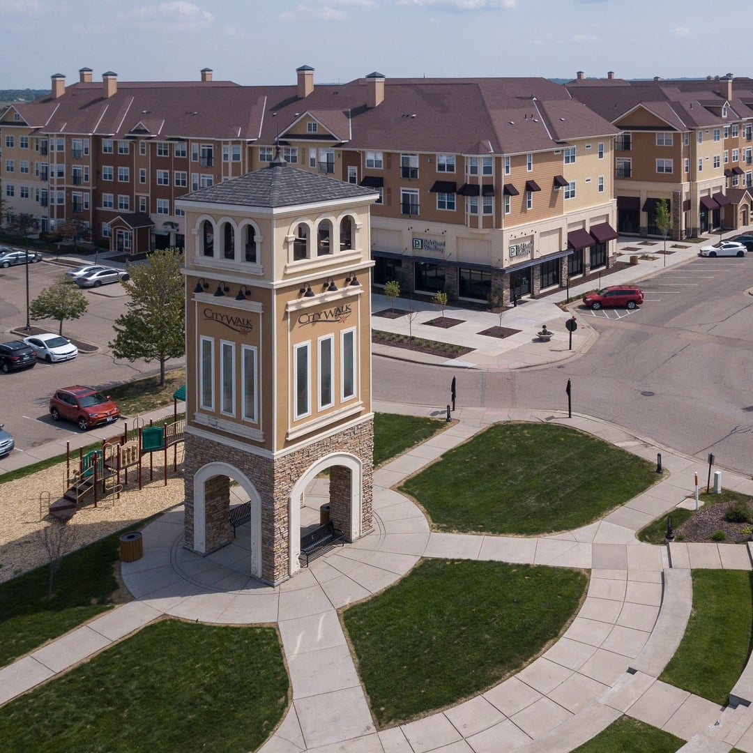 Aerial view of CityWalk at Woodbury, MN, a mixed-use apartment and retail community with a landmark tower, plaza, playground and green space