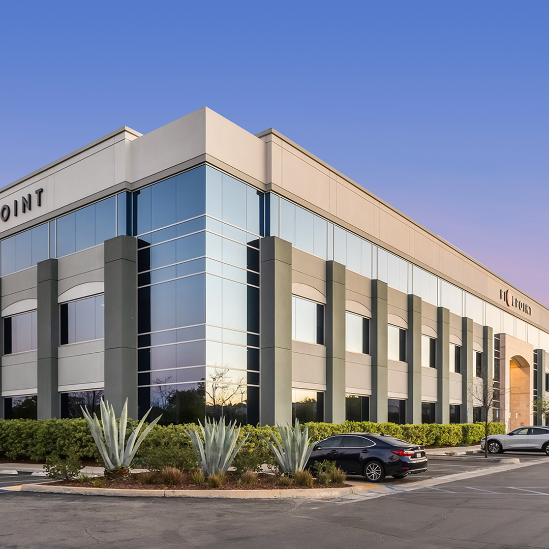 Exterior of Commons at Valencia office building in Valencia, California, with reflective glass windows, landscaping and surface parking.