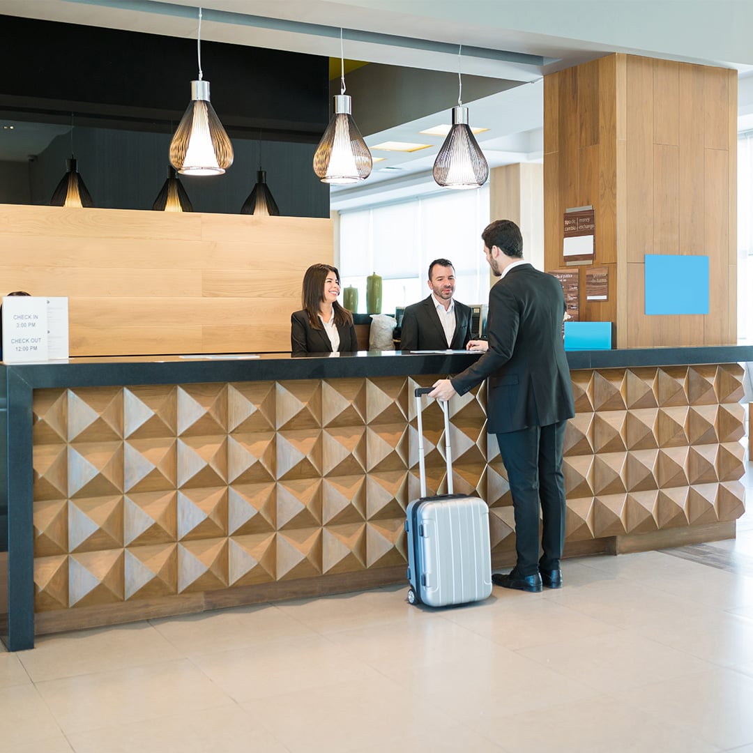 Two hotel workers assisting a customer at front desk