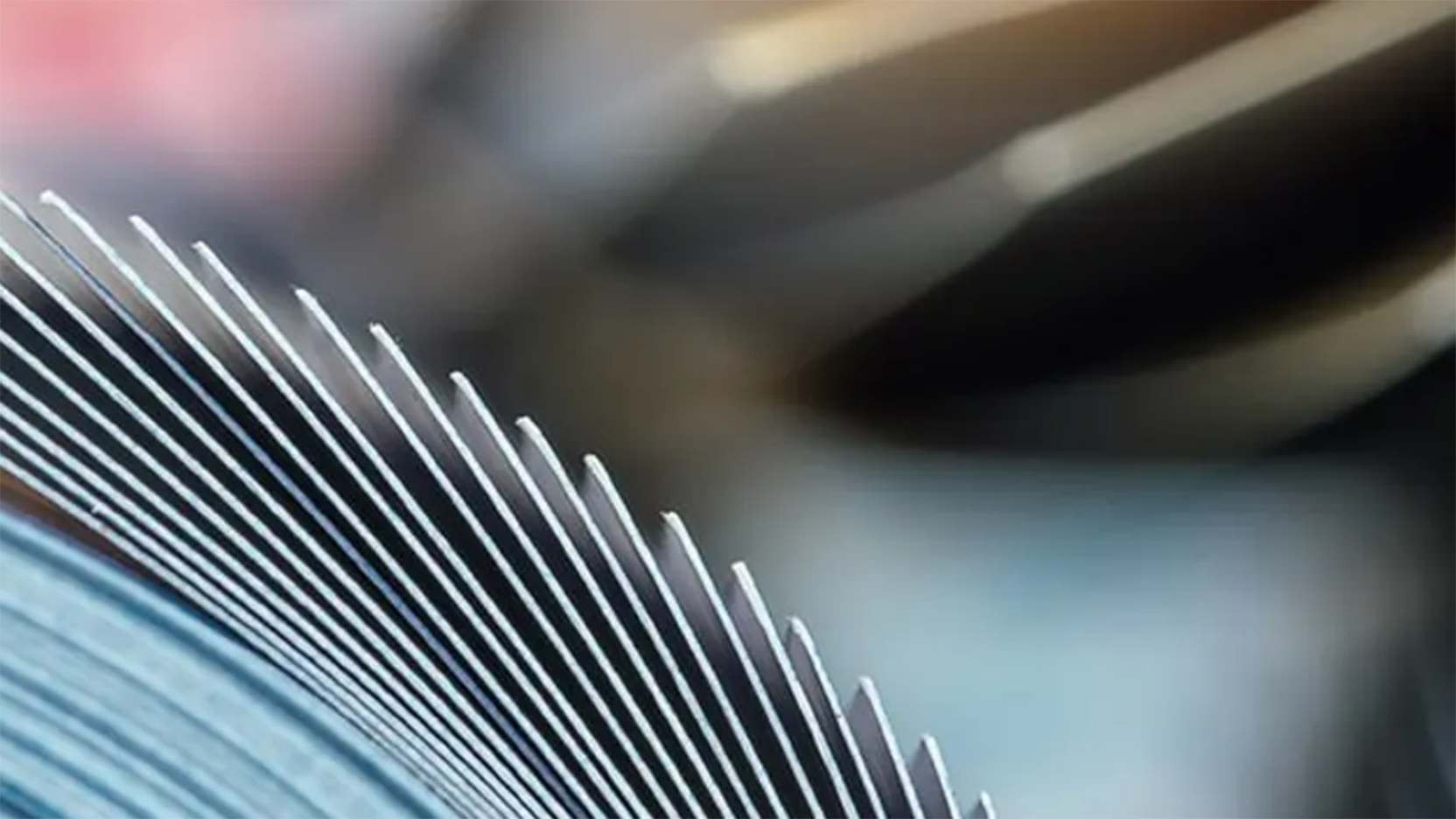 Close-up of metallic heat sink fins, showing parallel ridges and blurred background, representing technology or industrial cooling systems.