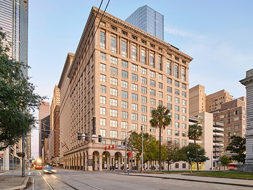 Street-level exterior of The Star, a historic multistory mixed-use apartment building in an urban downtown setting with palm trees and light rail.