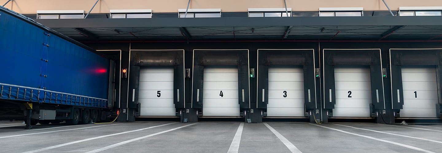Innovative modern logistics warehouse center complex building exterior bay gate semi-trailer unloading goods distribuition warm blue sunset sky background. Cargo storage facility industry