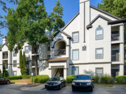 Garden‑style apartment community with pitched roofs and surface parking at Grande Club