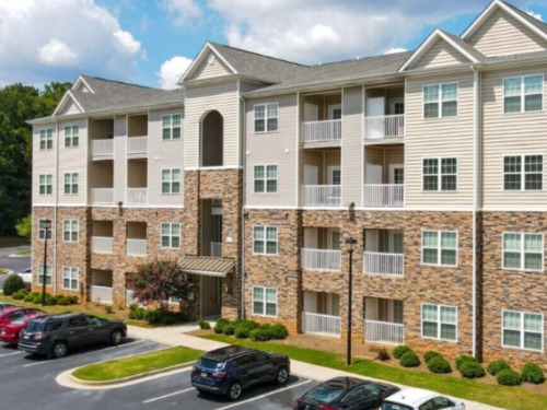 Garden‑style apartment community with balconies and surface parking at Hawthorne at Mirror Lake