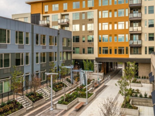 Modern courtyard‑style apartment community with landscaped walkways at Peloton Apartments