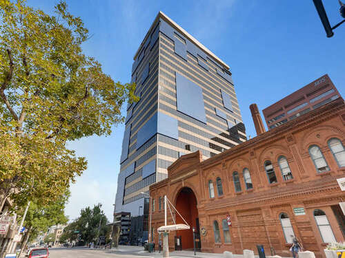 1800 Larimer modern glass office tower rising above a historic red brick building in downtown Denver, Colorado on a sunny day