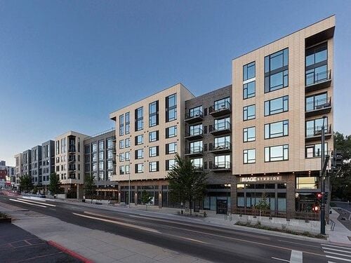 24Fifty apartment community exterior showing modern multi-story residential building with ground-floor retail including Image Studios along an urban street