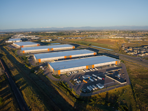 Aerial view of 76 Commerce Center industrial park featuring multiple large warehouse distribution buildings with orange accents and truck loading docks