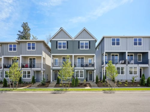 Holmes Park residential townhome community showing a row of modern three-story townhouses with balconies, board-and-batten siding, and landscaped front yards
