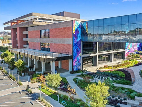 A modern mixed-use office building with colorful mural accents and landscaped outdoor areas.