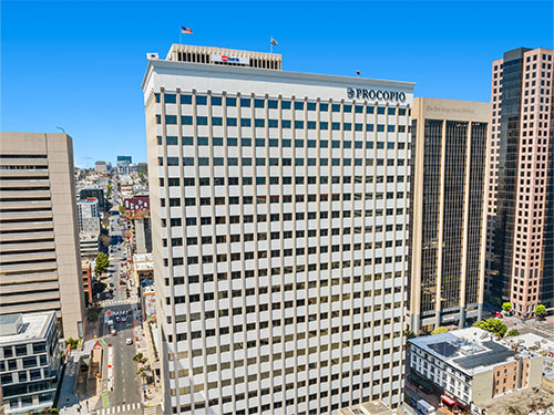 A tall downtown office tower with a grid-pattern façade surrounded by other high-rise buildings.